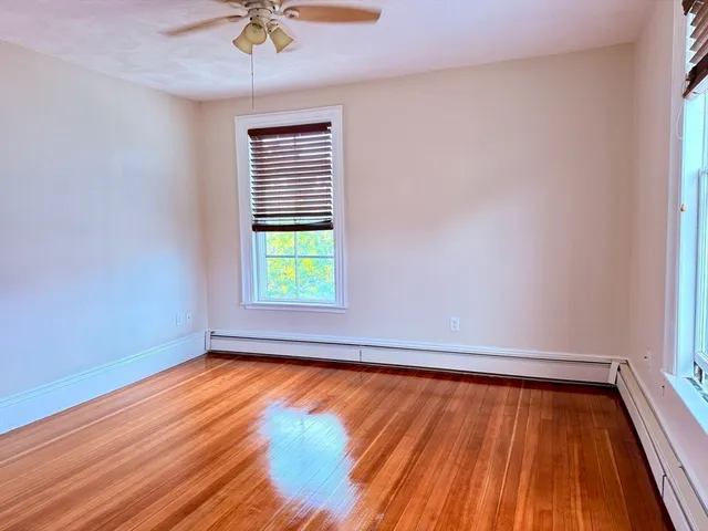 a view of an empty room with a window and wooden floor
