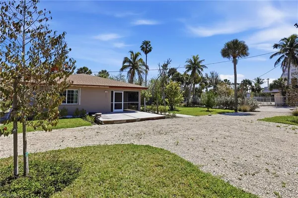 a view of a house with a yard and palm trees