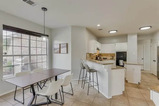 a kitchen with stainless steel appliances kitchen island granite countertop a table chairs and a refrigerator