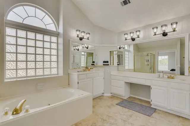 a bathroom with a bathtub a sink a vanity and a window