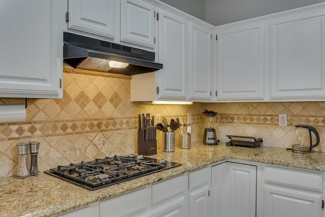 a kitchen with white cabinets and a stove