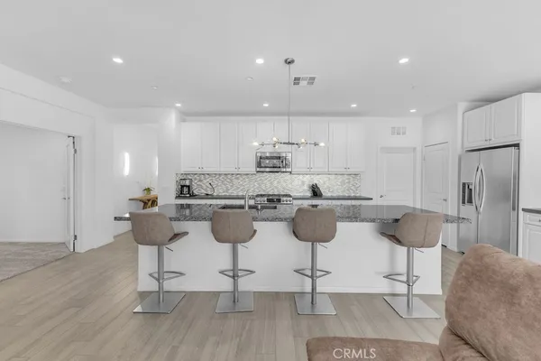 a kitchen with a dining table chairs sink and white cabinets