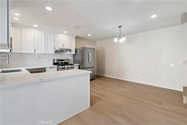 a kitchen with kitchen island a sink stainless steel appliances and white cabinets