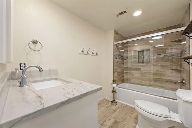 a bathroom with a granite countertop sink a toilet and shower