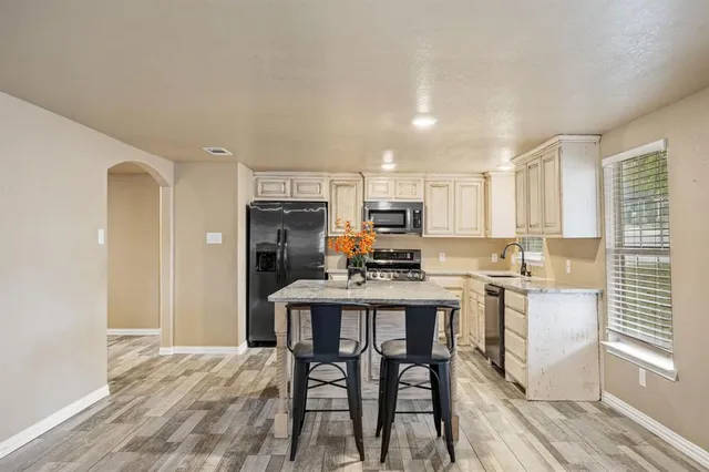 a kitchen with kitchen island a dining table chairs appliances and cabinets