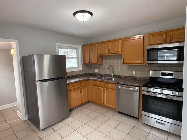 a kitchen with granite countertop a refrigerator and a stove top oven