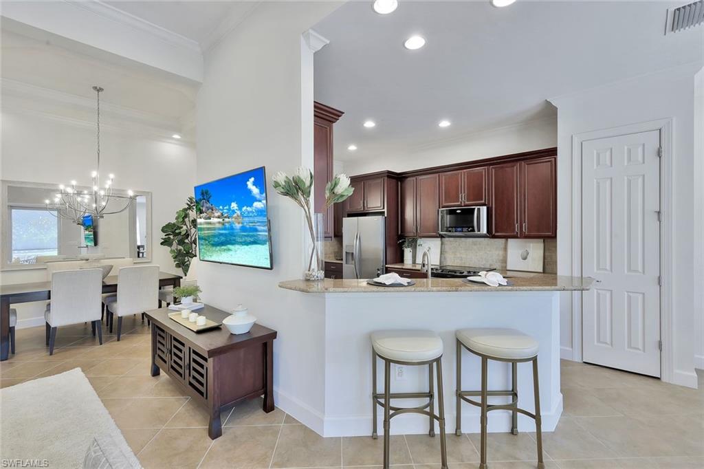 9058 Limestone Lane Naples, FL 34120 - Photo 8 of 48 a kitchen with kitchen island granite countertop wooden cabinets and stainless steel appliances