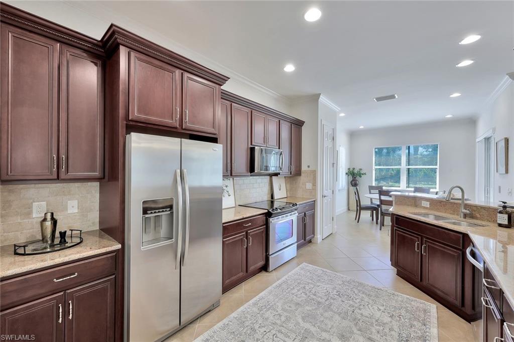 9058 Limestone Lane Naples, FL 34120 - Photo 10 of 48 a kitchen with granite countertop stainless steel appliances and wooden cabinets