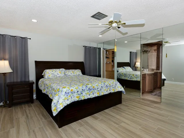 a bedroom with a large bed a chandelier and dresser