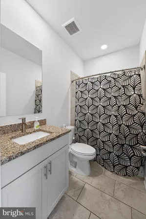a bathroom with a granite countertop toilet and a sink