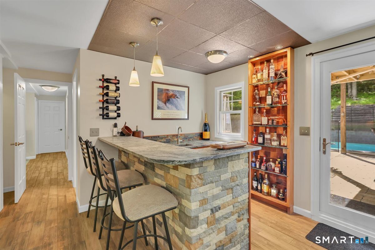 122 Ridgeview Circle Guilford, CT 06437 - Photo 23 of 40 The built-in wet bar off the rec room features tiled flooring and a leather-honed granite top, along with a Newair beverage cooler, microwave, and built-in display cabinetry; perfect for easy entertaining.