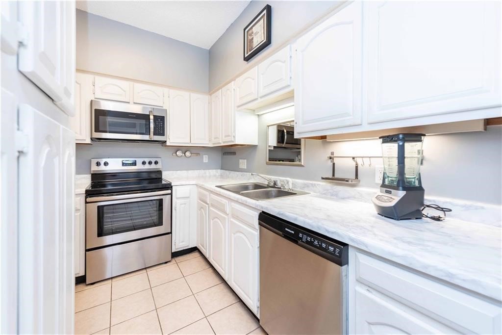 1910 Robbins Place, Unit 210 Austin, TX 78705 - Photo 6 of 13 a kitchen with granite countertop a stove sink and microwave