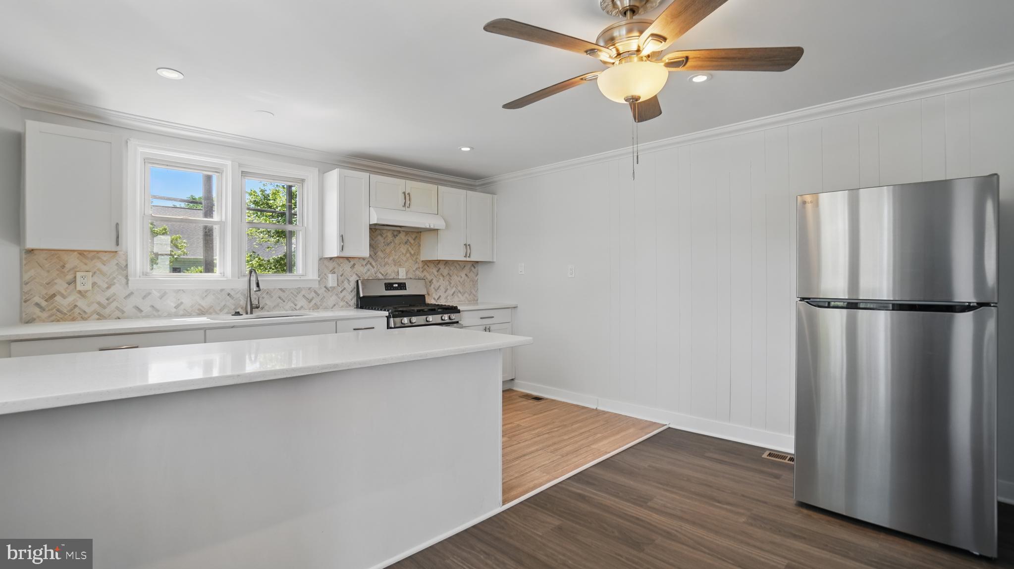 8014 Ritchie Highway Pasadena, MD 21122 - Photo 10 of 38 a kitchen with stainless steel appliances granite countertop a refrigerator a sink dishwasher a stove and white countertops with wooden floor