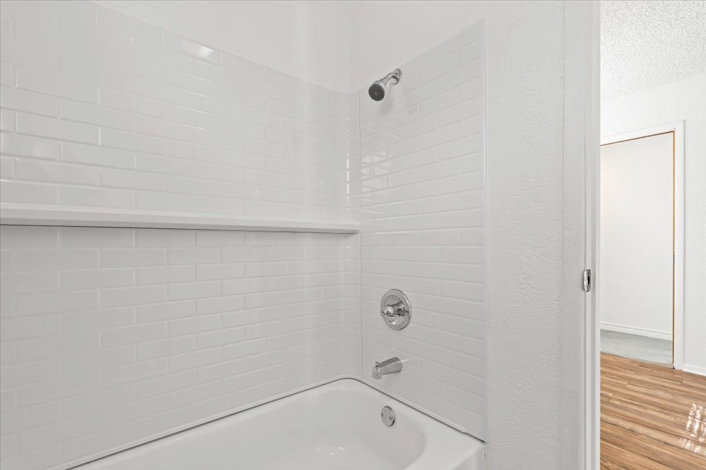 205 Cisneros Street Kyle, TX 78640 - Photo 13 of 17 Bathroom with shower / bathtub combination, wood finished floors, and a textured wall