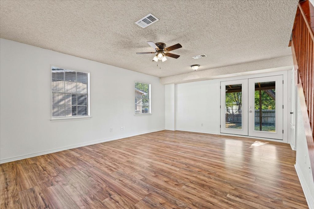 205 Cisneros Street Kyle, TX 78640 - Photo 2 of 17 Spare room featuring french doors, light wood-type flooring, healthy amount of natural light, and a textured ceiling