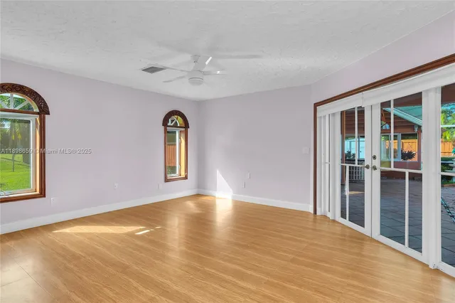 a view of an empty room with window and wooden floor