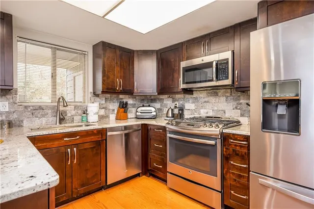 a kitchen with stainless steel appliances granite countertop a stove top oven a sink dishwasher and a refrigerator