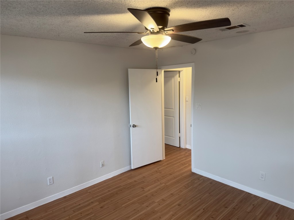 115 Waller Street, Unit A Austin, TX 78702 - Photo 11 of 18 Spare room with dark wood-style floors, a textured ceiling, and a ceiling fan
