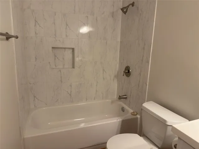 a white bath tub sitting next to a white toilet and a shower