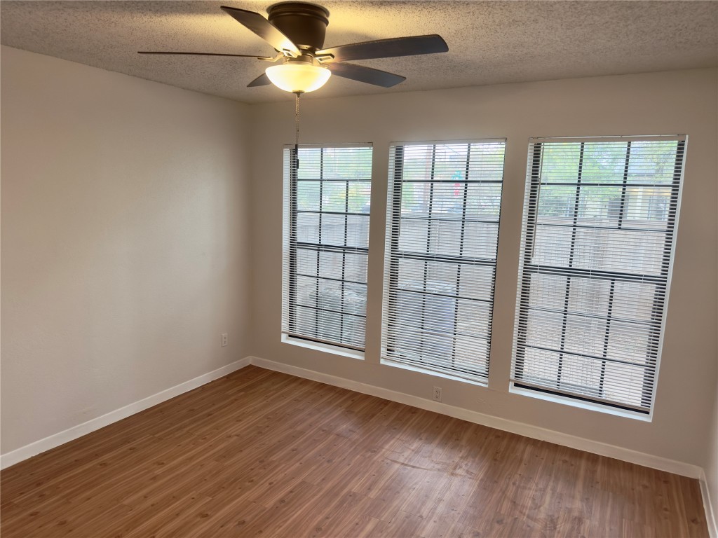 115 Waller Street, Unit A Austin, TX 78702 - Photo 9 of 18 Unfurnished room featuring wood finished floors, a textured ceiling, and a ceiling fan
