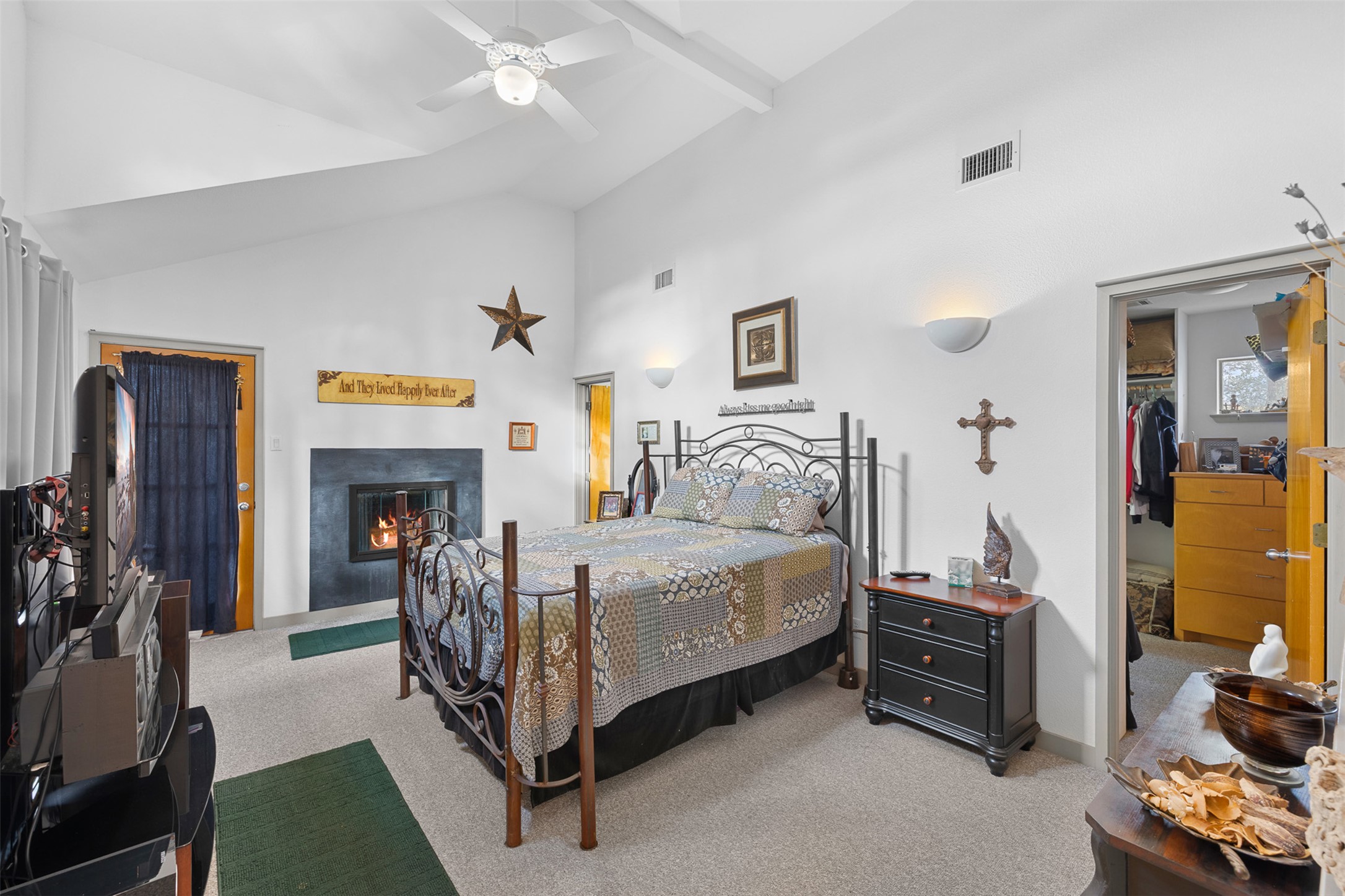 27701 Turner Ranch Road Marble Falls, TX 78654 - Photo 9 of 40 Bedroom featuring high vaulted ceiling, carpet floors, a spacious closet, a glass covered fireplace, and a ceiling fan