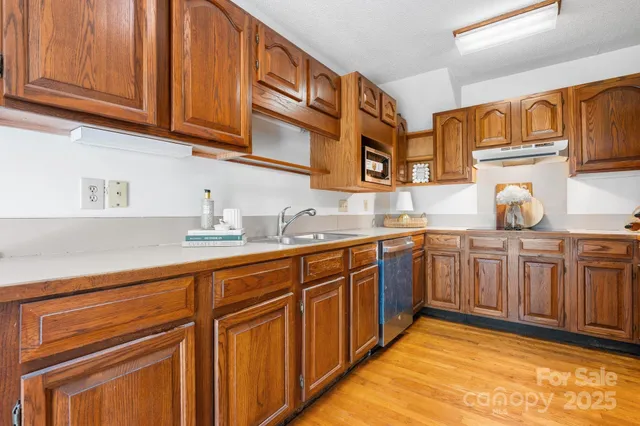 a kitchen with stainless steel appliances granite countertop wooden cabinets a sink and dishwasher