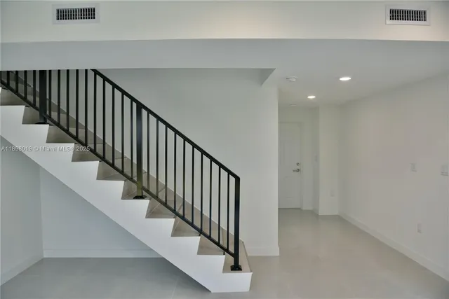 a view of staircase with railing and white walls