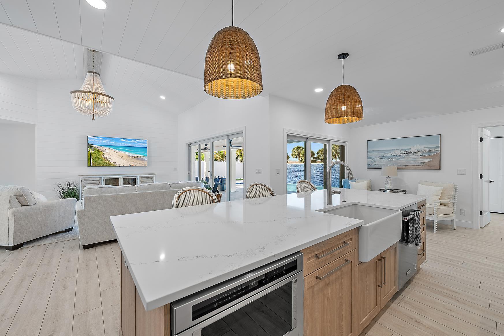 491 Sunset Way Juno Beach, FL 33408 - Photo 18 of 50 a kitchen with a sink a stove and chairs with wooden floor