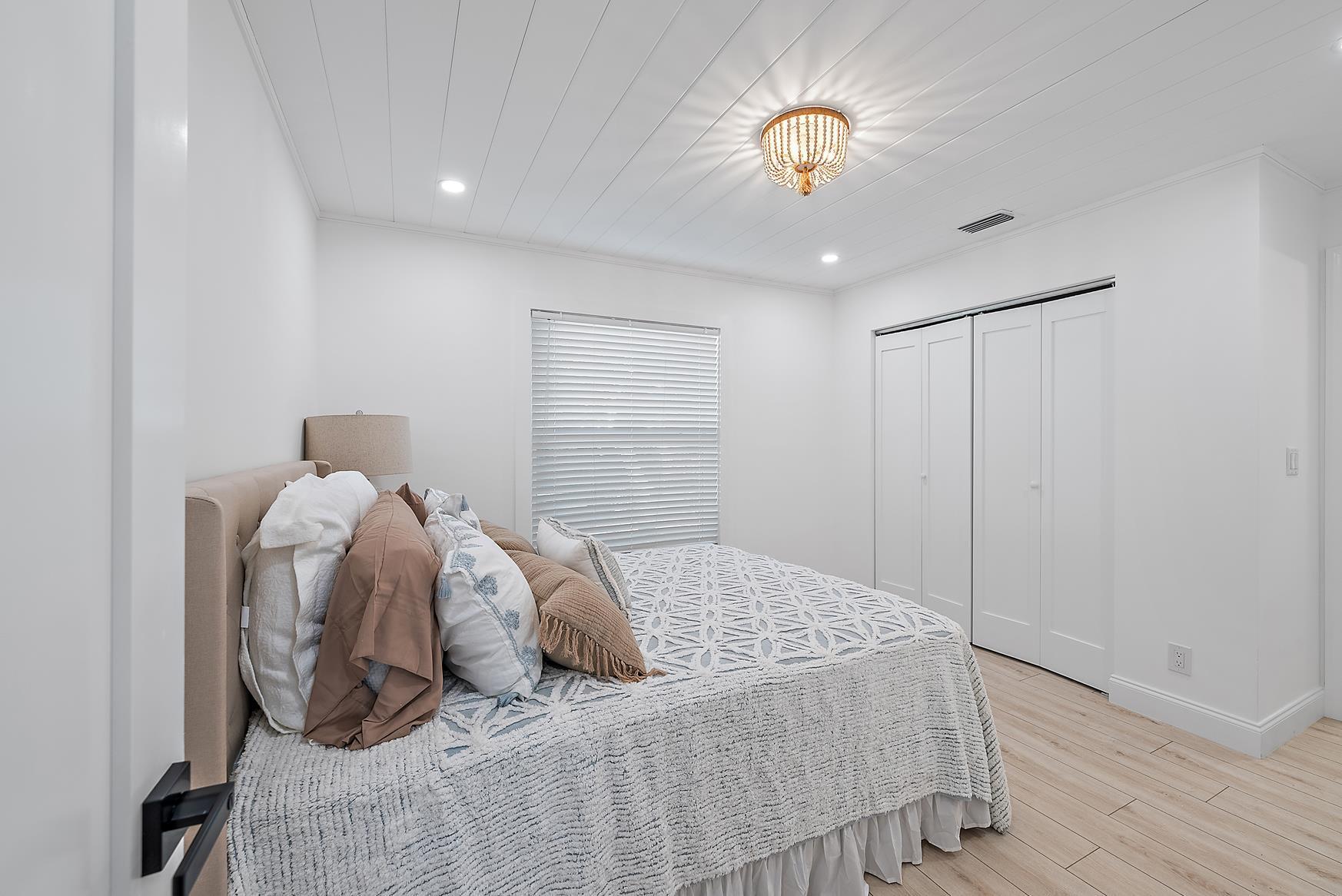 491 Sunset Way Juno Beach, FL 33408 - Photo 30 of 50 a bedroom with a bed and a chandelier