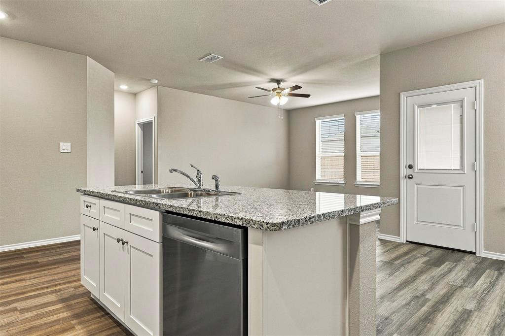 15932 Stableford Road Justin, TX 76247 - Photo 7 of 35 Kitchen island with a double basin stainless steel sink, stainless steel dishwasher, and a light-toned countertop