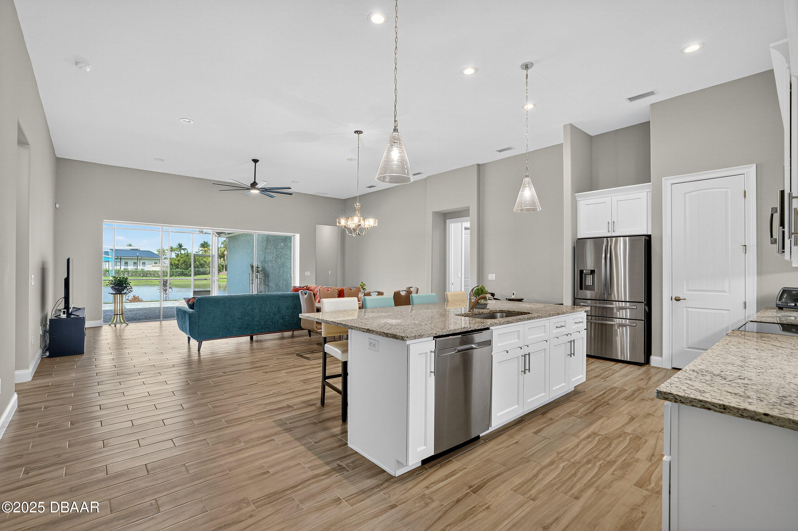 212 Fuchsia Street Daytona Beach, FL 32124 - Photo 5 of 54 a kitchen with stainless steel appliances kitchen island granite countertop a stove a refrigerator a sink and a dining table with wooden floor