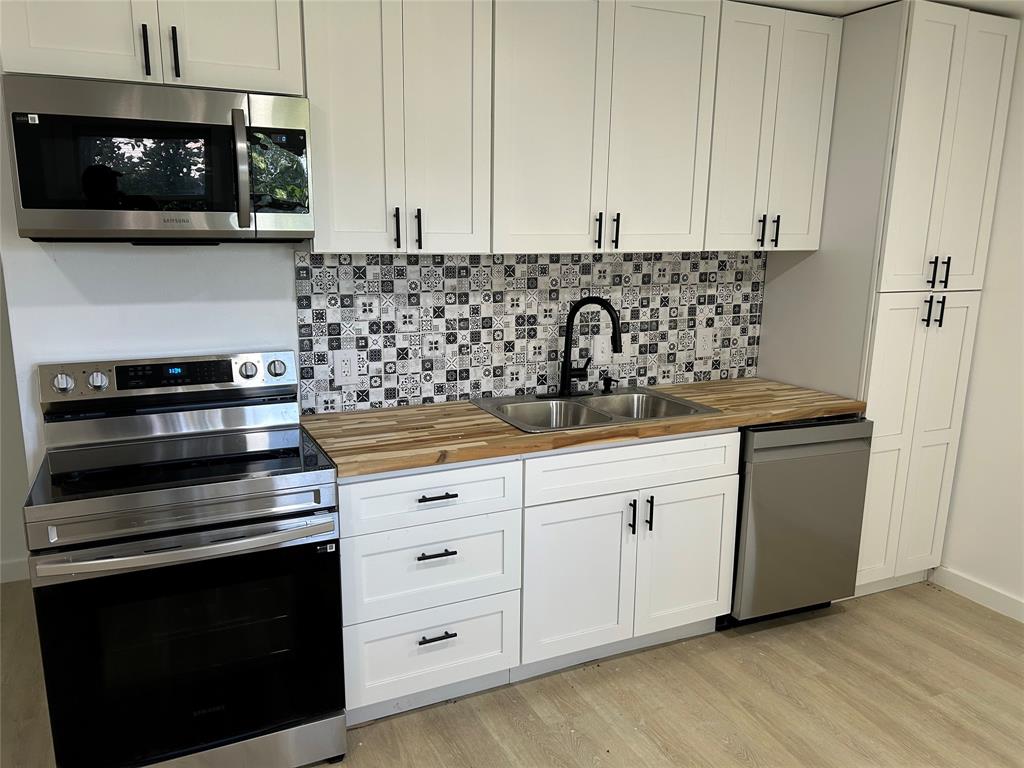 a kitchen with granite countertop white cabinets and stainless steel appliances