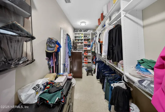 a view of walk in closet with clothes and shoes