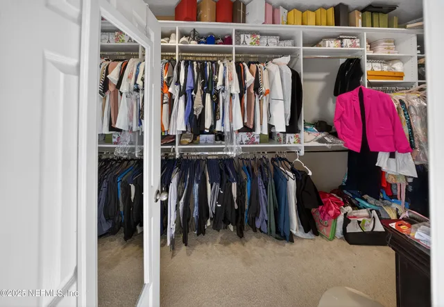 a view of walk in closet with clothes and shoes