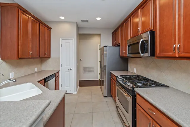 a kitchen with stainless steel appliances granite countertop a refrigerator a stove a sink and dishwasher