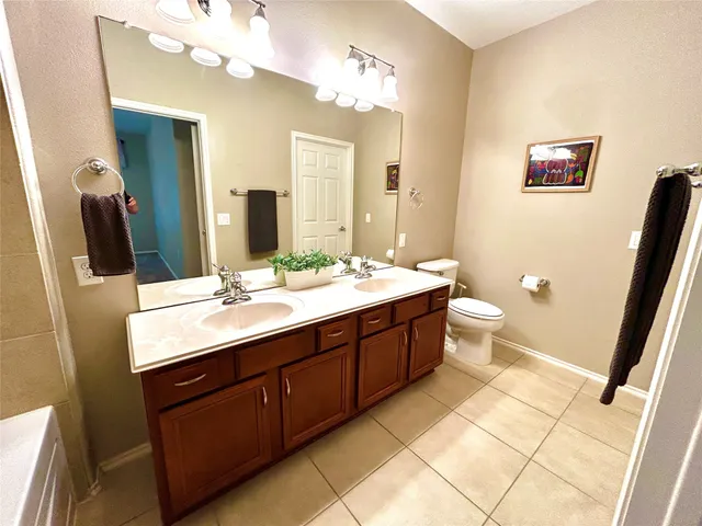 a bathroom with a double vanity sink a mirror and a toilet