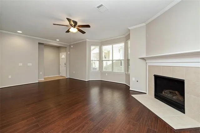 an empty room with wooden floor fireplace and windows
