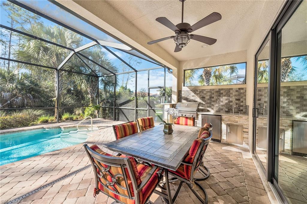 4359 Raffia Palm Circle Naples, FL 34119 - Photo 20 of 35 a view of a patio with a table chairs and a floor to ceiling window