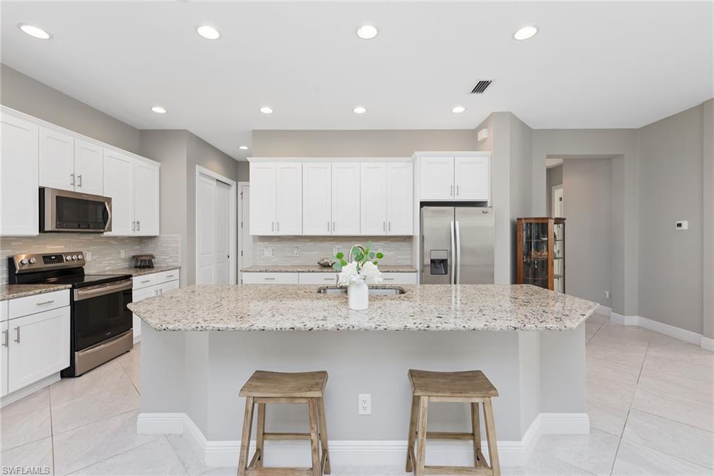 4359 Raffia Palm Circle Naples, FL 34119 - Photo 5 of 35 a kitchen with stainless steel appliances granite countertop a sink and cabinets