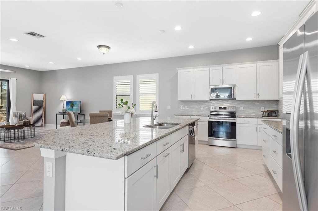 4359 Raffia Palm Circle Naples, FL 34119 - Photo 6 of 35 a kitchen with stainless steel appliances granite countertop a sink stove and cabinets