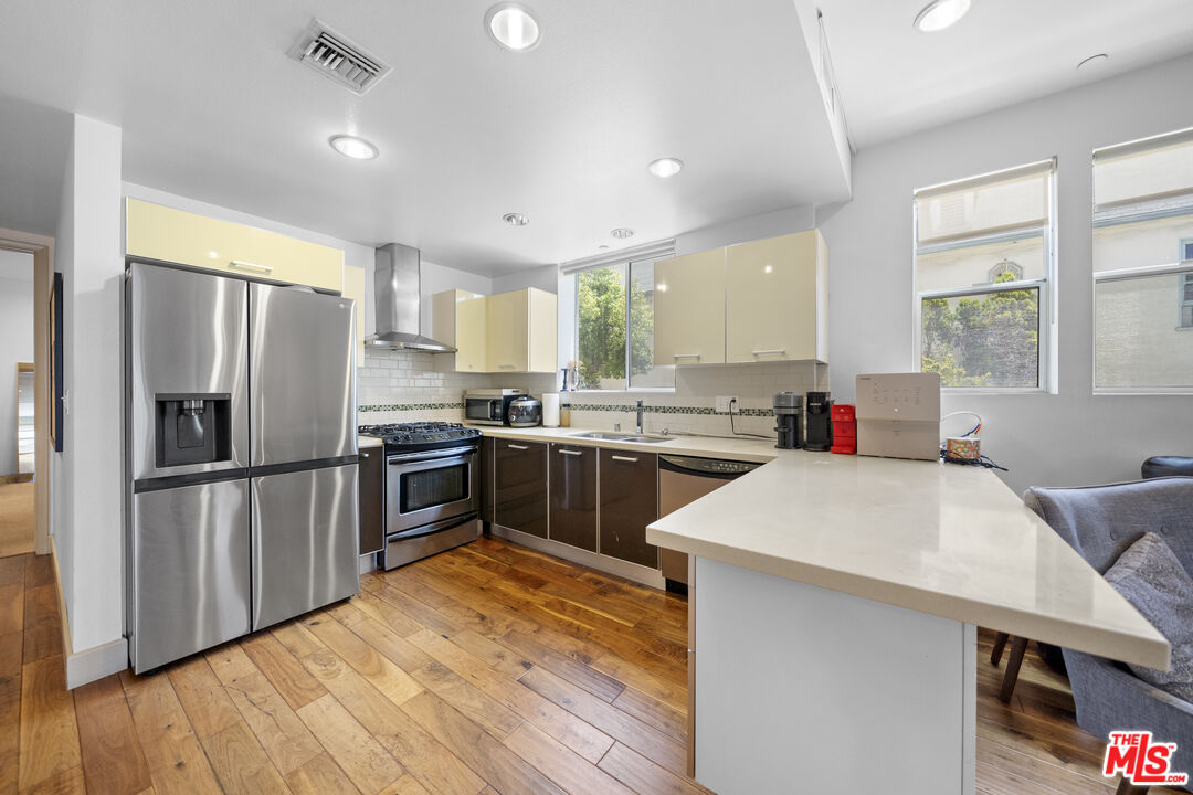 848 Irolo Street, Unit 105 Los Angeles, CA 90005 - Photo 13 of 18 a kitchen with a refrigerator a sink dishwasher and a stove with wooden floor