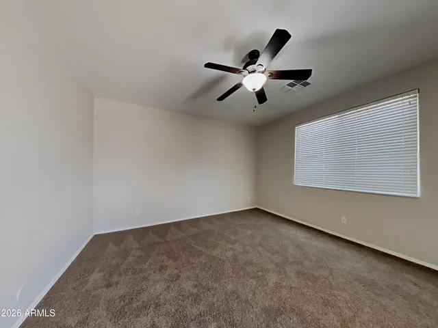 an empty room with a window and a ceiling fan