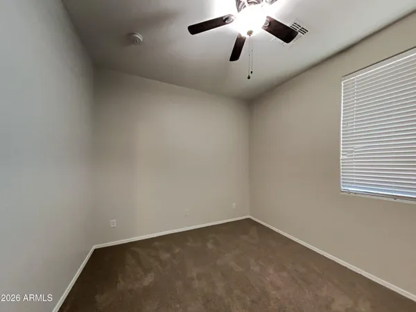an empty room with a chandelier fan and windows