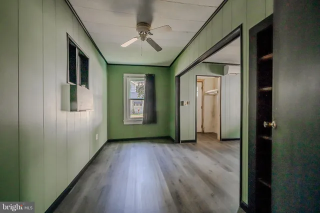 an empty room with wooden floor closet and windows