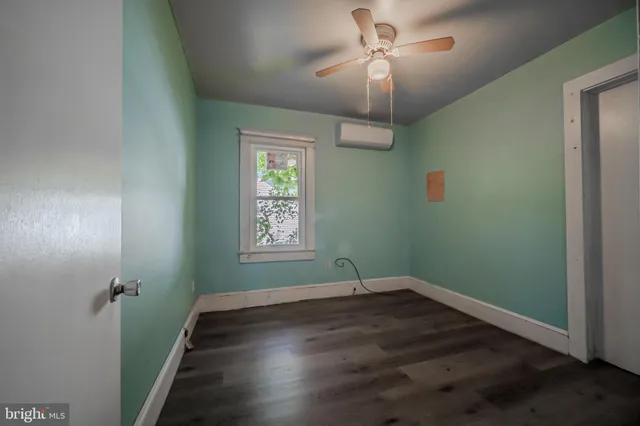 an empty room with wooden floor chandelier fan and windows