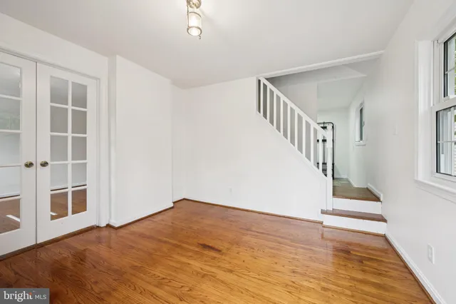 a view of an entryway with wooden floor leading to a furnished livingroom and windows