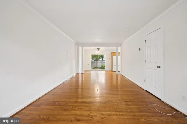 a view of empty room with wooden floor and window