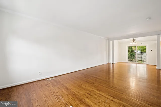 a view of an empty room with wooden floor and windows