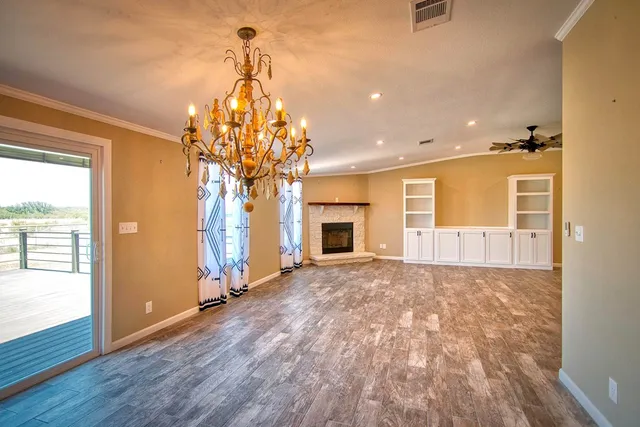 an empty room with chandelier fan and windows