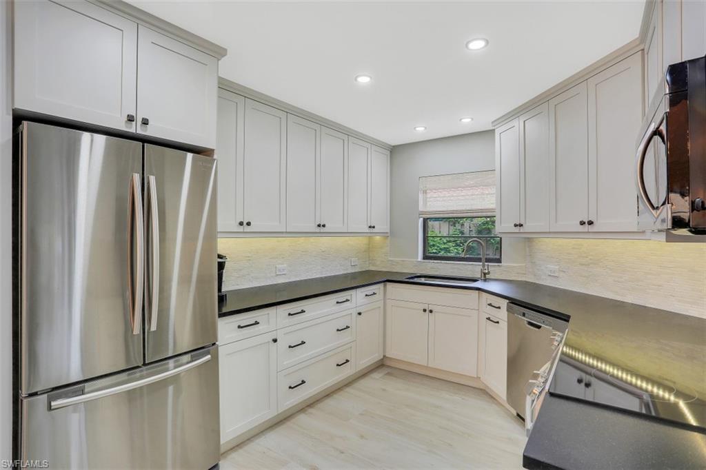 714 Reef Point Circle Naples, FL 34108 - Photo 7 of 27 a kitchen with white cabinets and stainless steel appliances